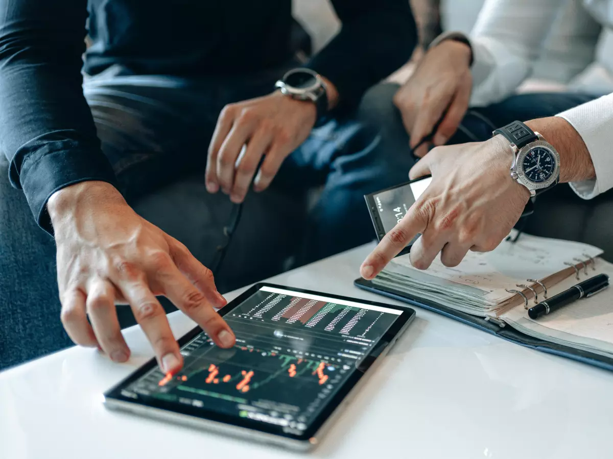 Two people looking at a tablet showing financial data, one is pointing at the screen.