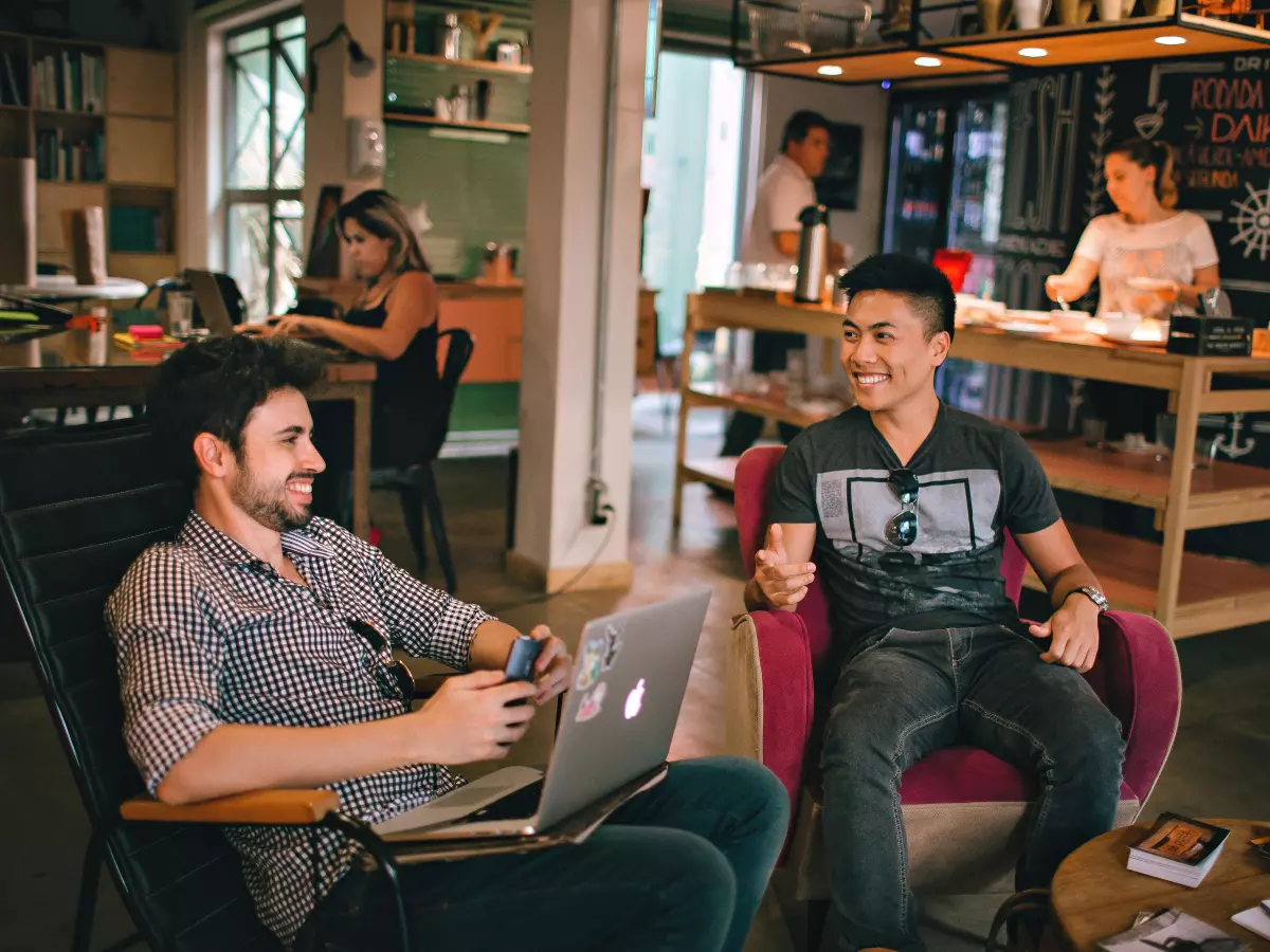 Two men sitting in chairs with a laptop