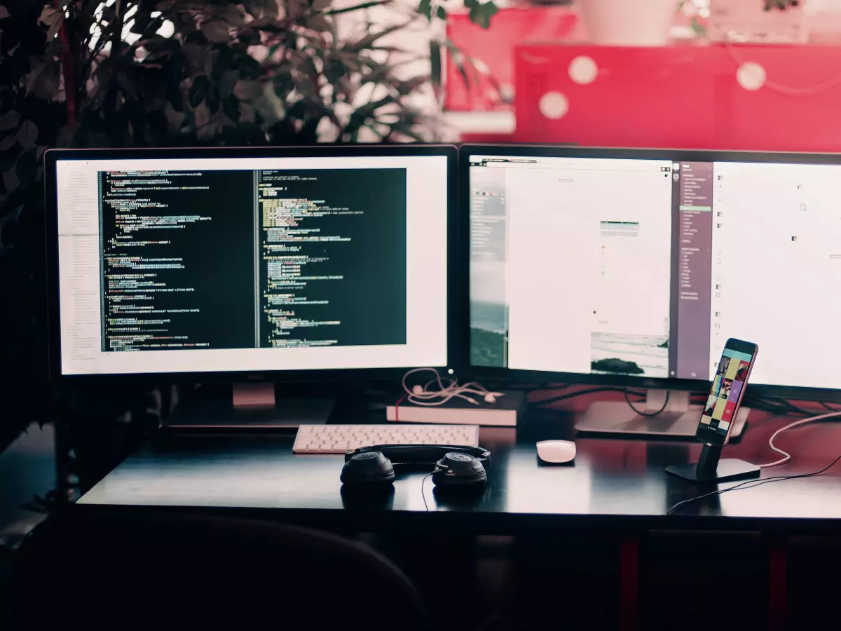 A developer's workspace with two monitors showing code and a smartphone.