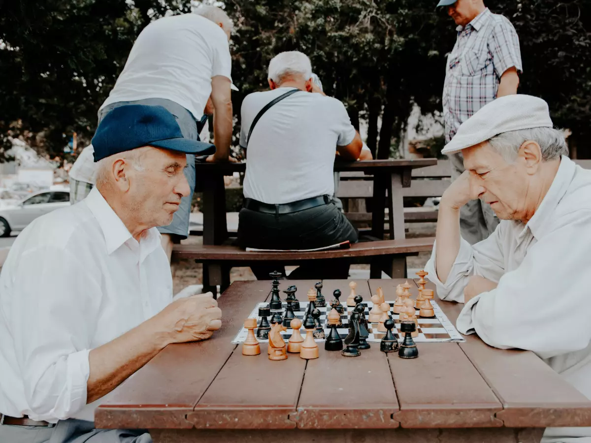 Two elderly men are playing chess in a park.