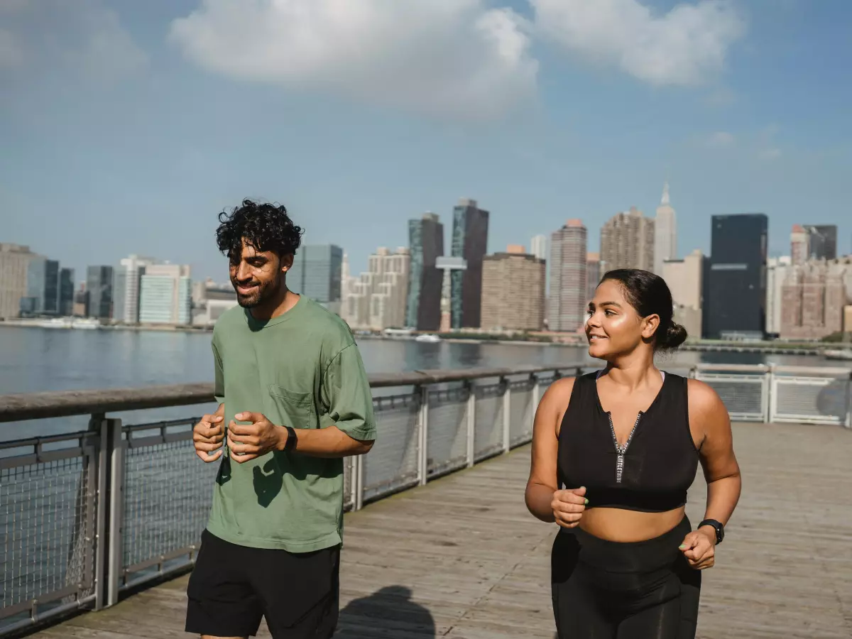 Two people jogging in front of a cityscape.