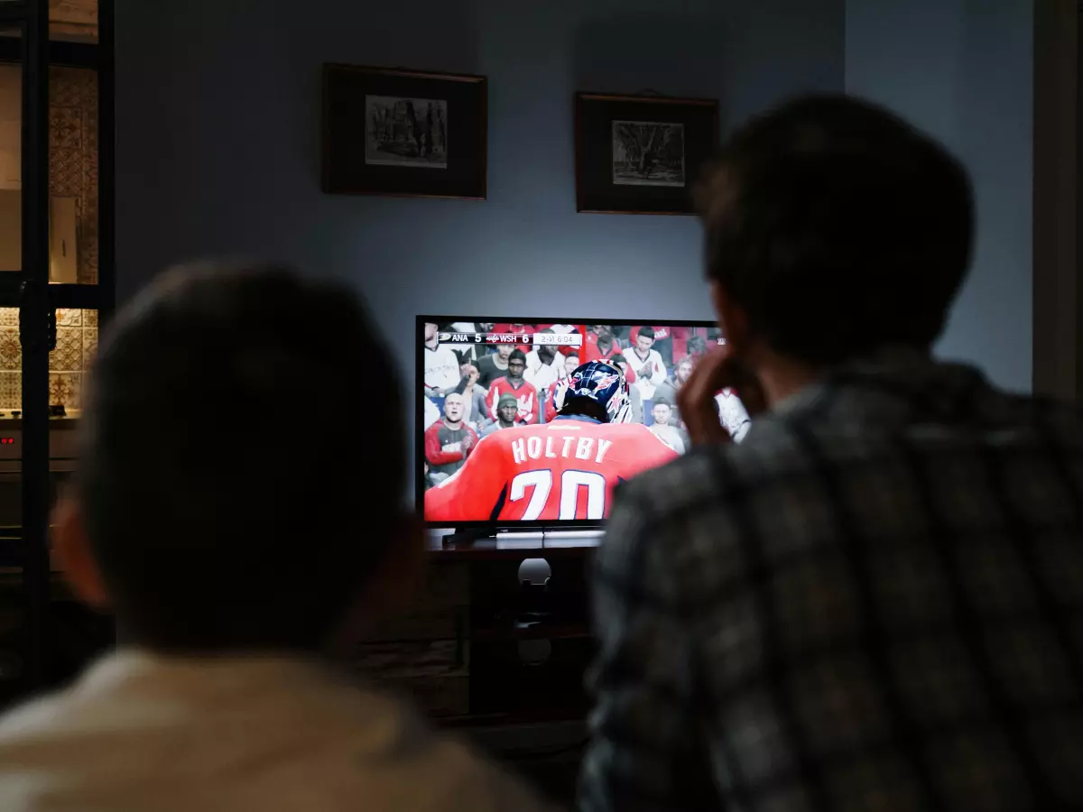 A couple watching a sporting event on a TV.