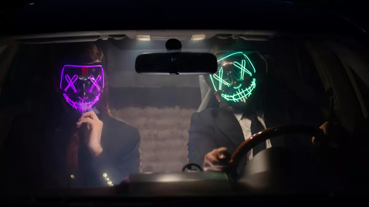 Two people wearing LED masks inside a car at night