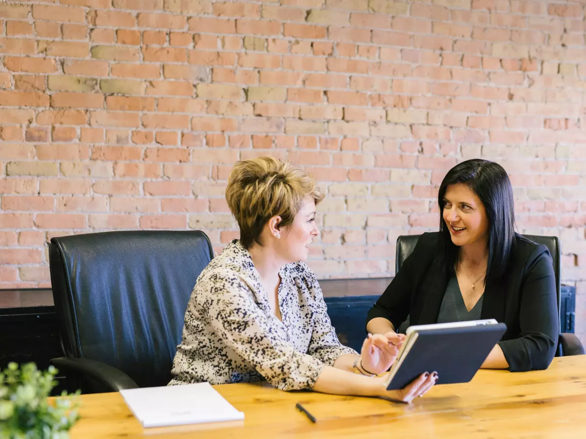 Two women in a professional setting discussing something on a tablet