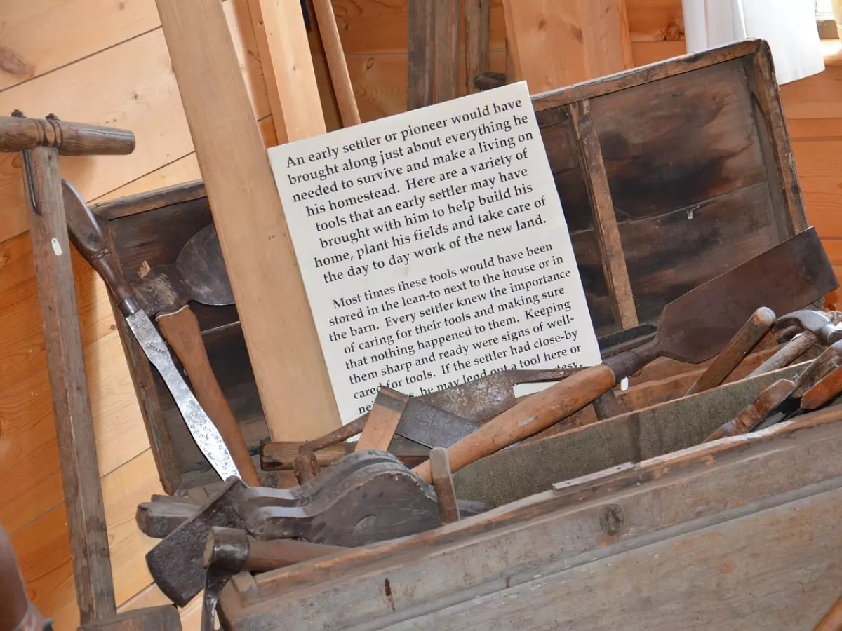 A wooden chest full of tools, with a text about early settlers and their tools.