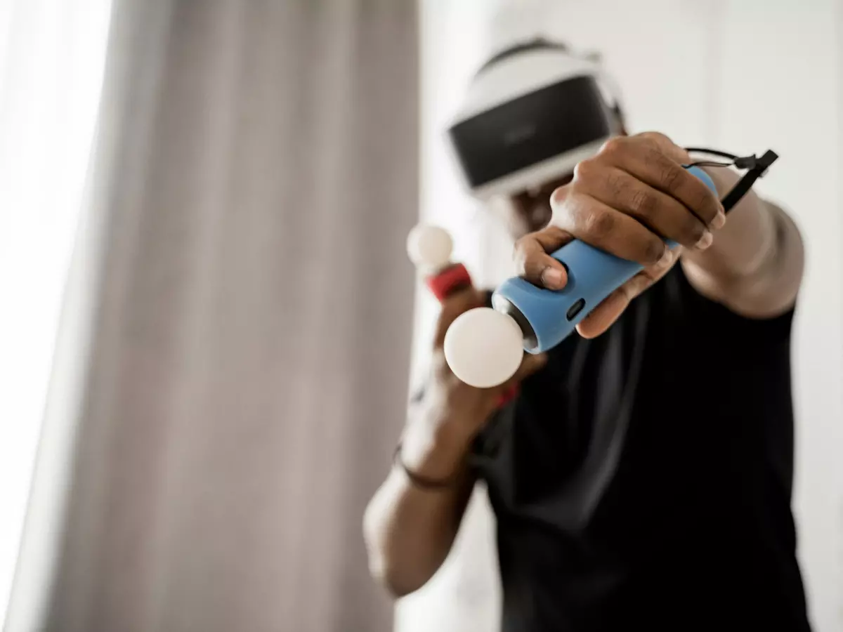 A person wearing a VR headset is holding controllers and looking intensely into the distance.