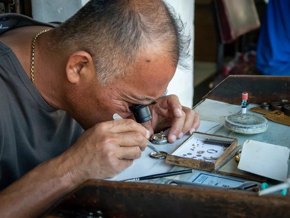 A man is working on a watch with a magnifying glass.