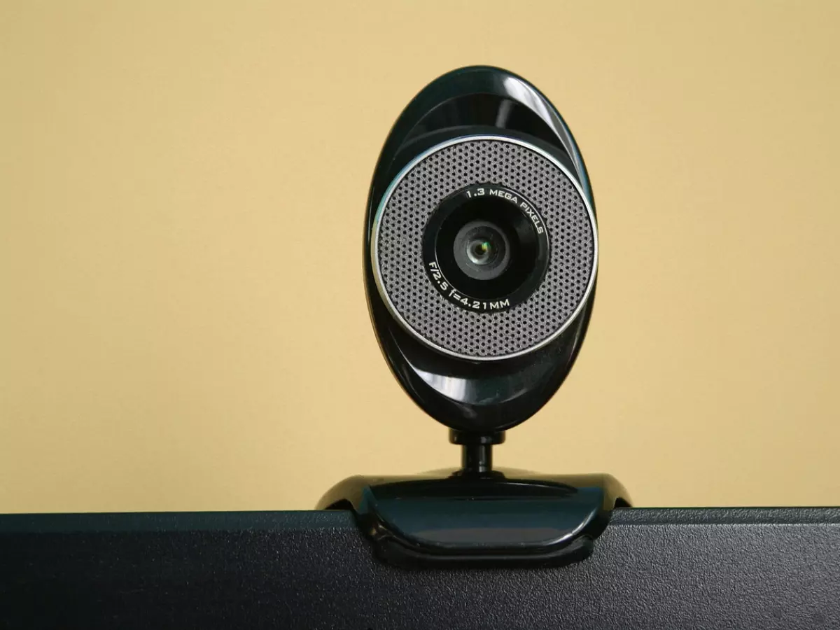 A close-up of a black webcam mounted on a laptop screen, showcasing its design and lens details.