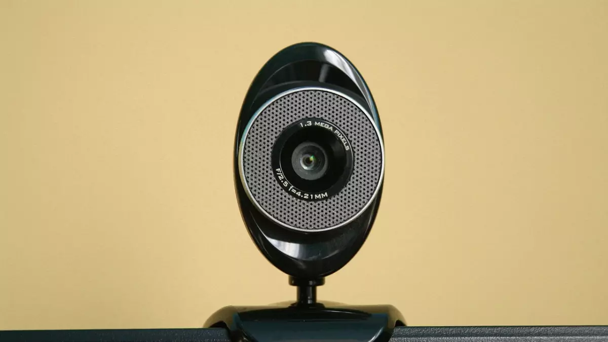 A close-up of a black webcam mounted on a laptop screen, showcasing its design and lens details.