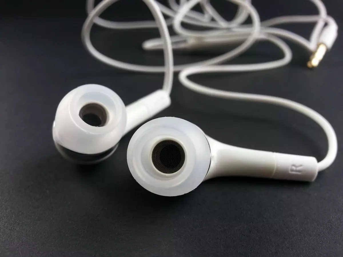 Close up of a pair of white wired earphones with transparent ear tips.