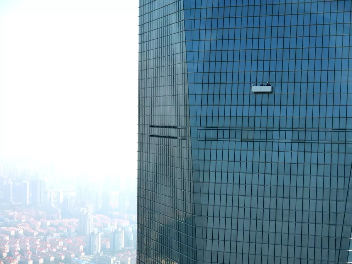 A window cleaner on a platform cleaning the windows of a high-rise building.