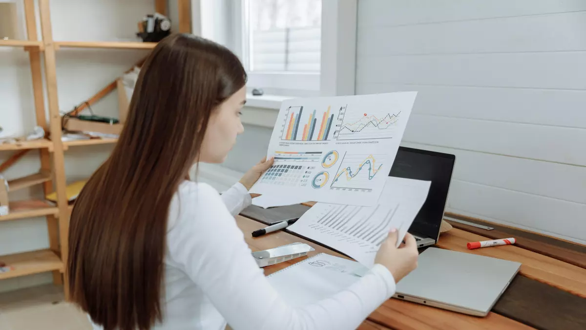 A woman sitting at a desk and looking at data charts. 