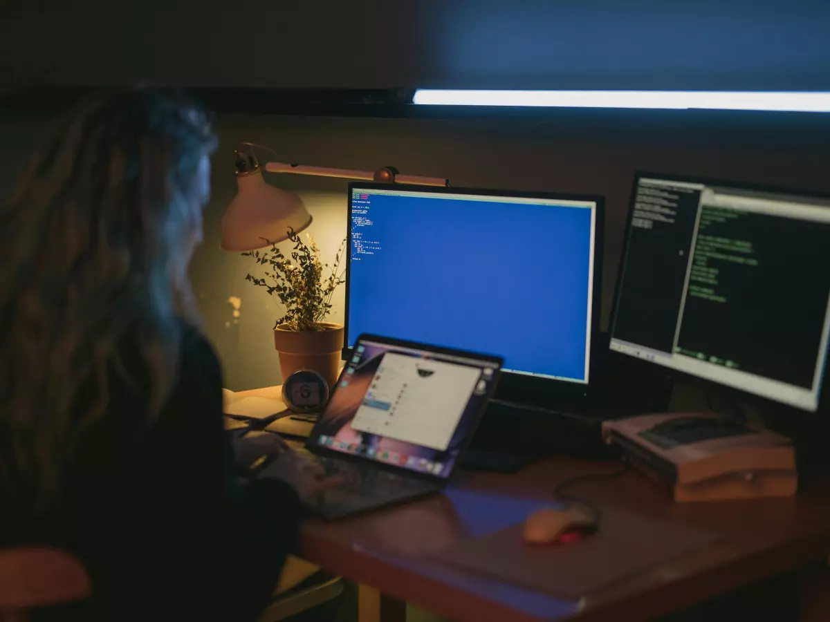 A person is working on a computer with multiple screens, one showing code.