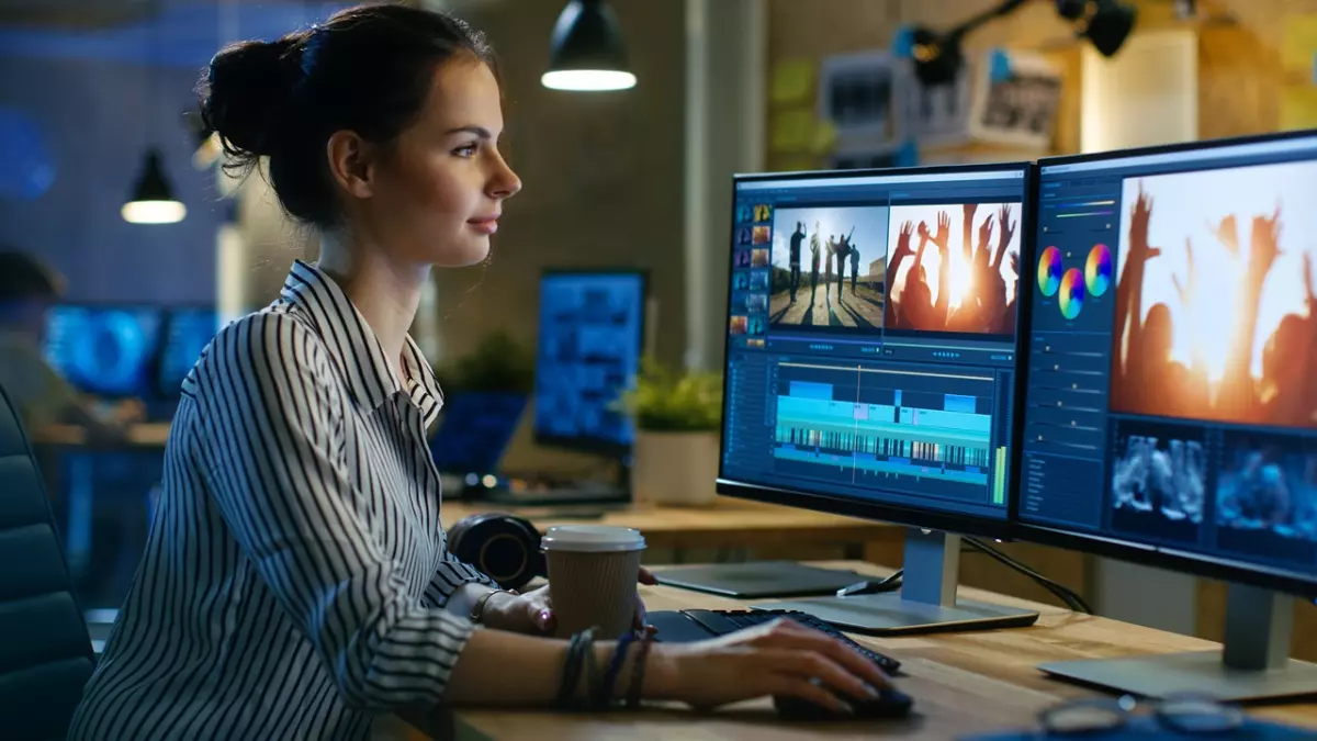 A woman working on a computer, editing a video.