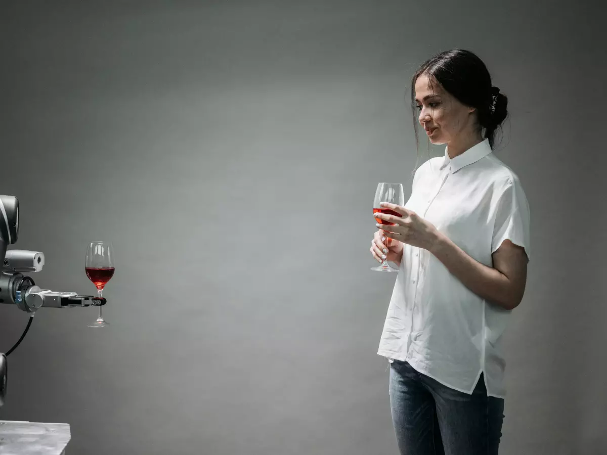 A robotic arm pouring wine into a glass held by a woman, showcasing precise movement and control.