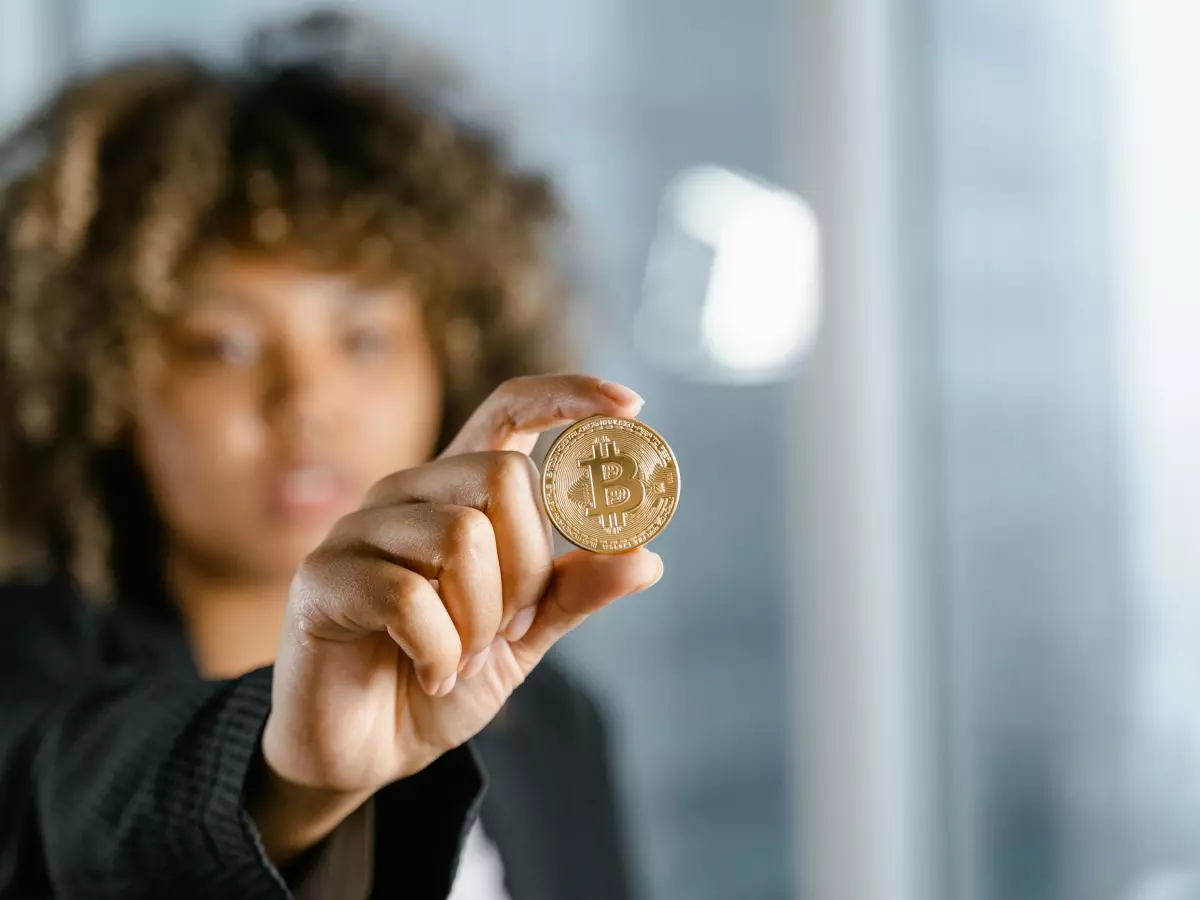 A woman is holding a Bitcoin coin