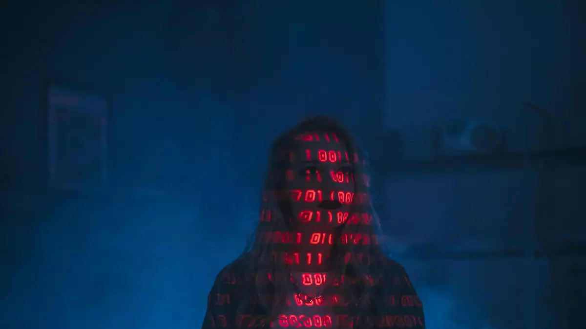 A person in a hooded jacket stands in a dimly lit room, their face obscured by a glowing red code that appears to be forming a digital mask. Blue smoke or mist fills the background, creating an eerie atmosphere. 