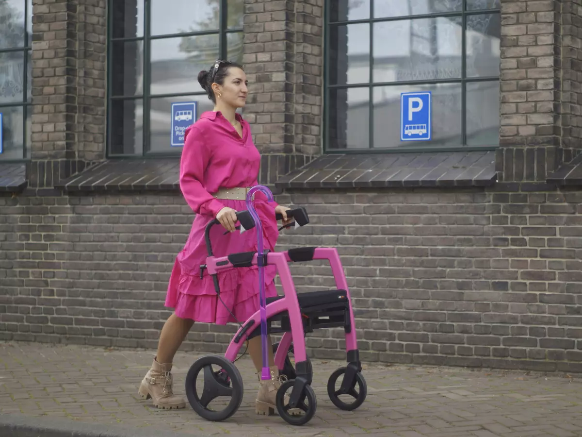 A woman walking with a pink walker.