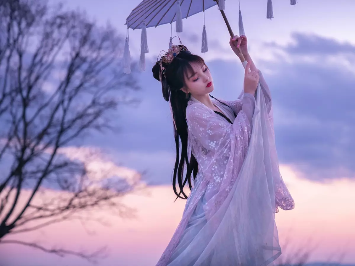 A woman in a traditional Chinese dress with a white parasol stands against a purple sky.