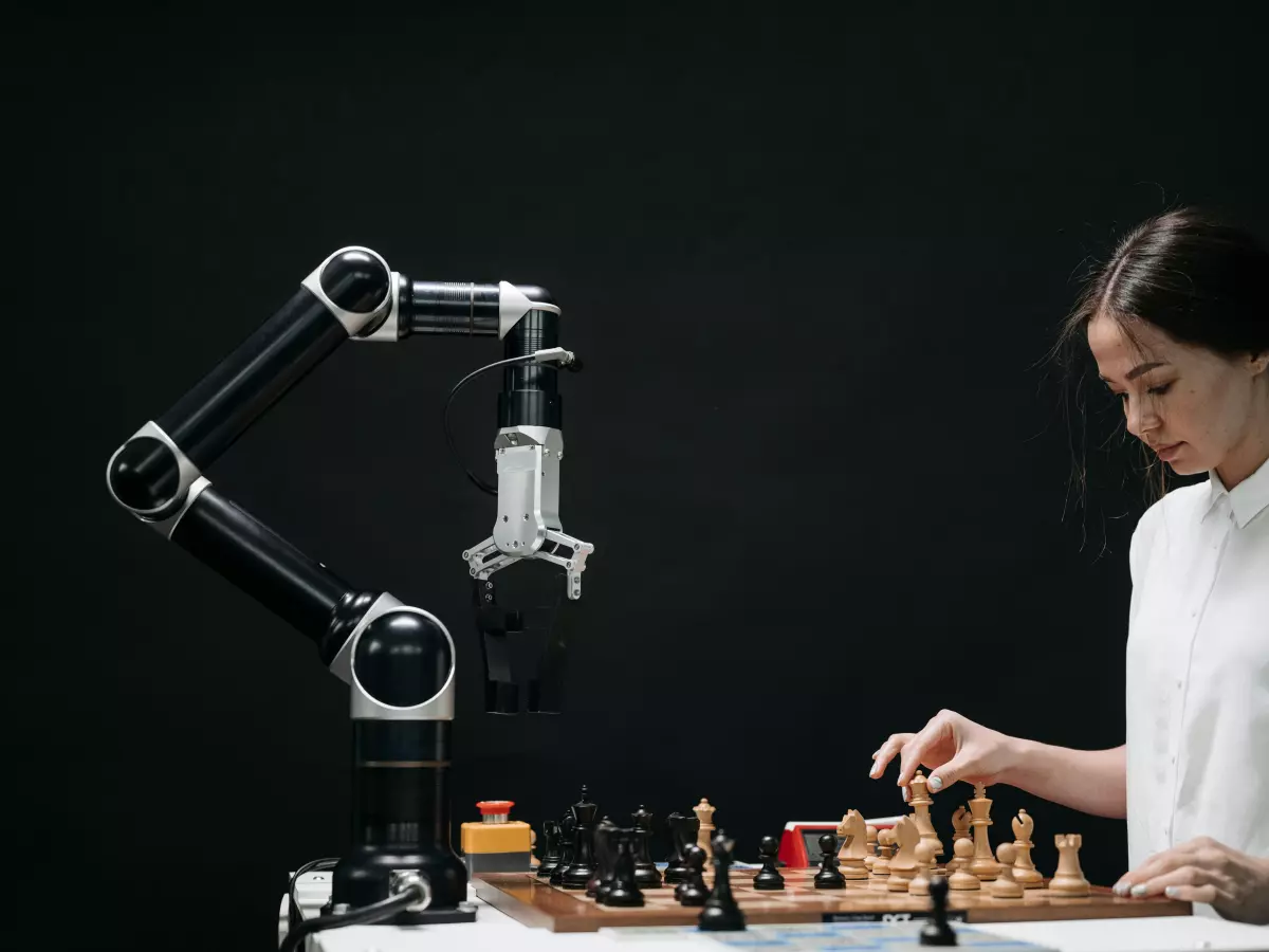 A woman plays chess against a robotic arm.