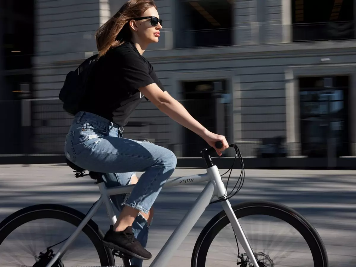 A woman riding an electric bicycle in a city setting with a blurred background.