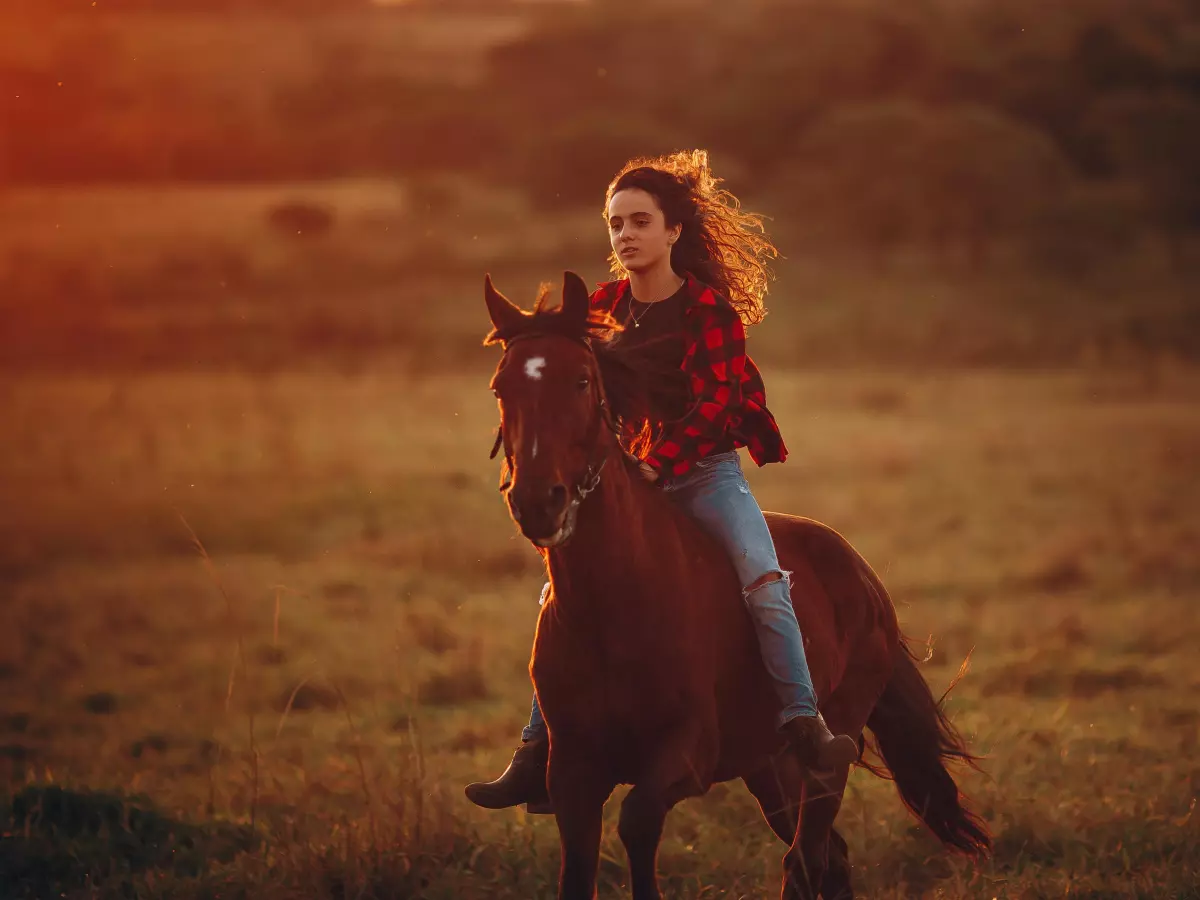 A young woman is riding a horse in a field.