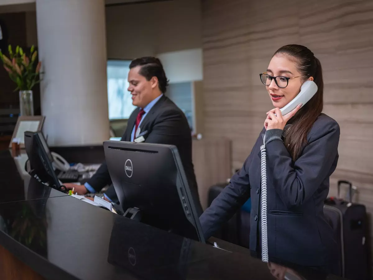 A hotel check-in counter with a person using a phone.