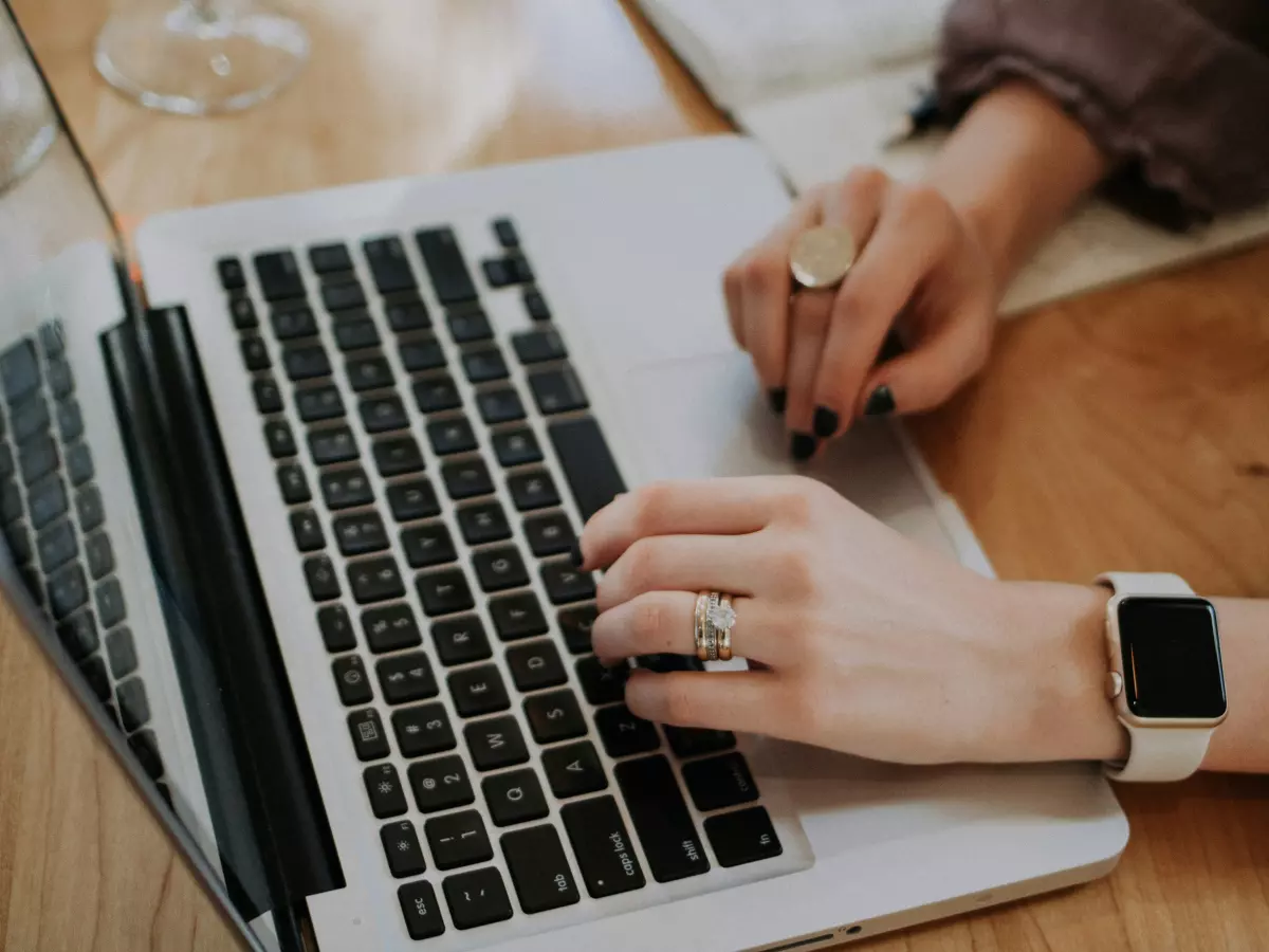 A close-up of a person's hands typing on a laptop.