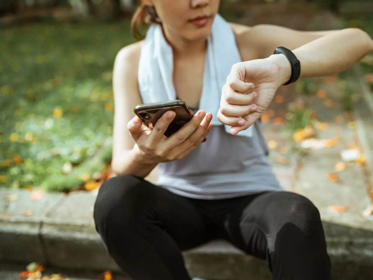 A woman wearing a smartwatch and using a smartphone.