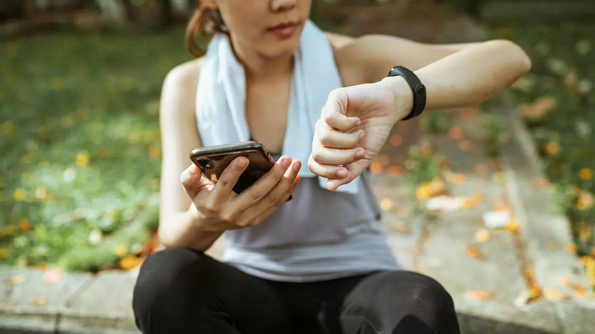 A woman wearing a smartwatch and using a smartphone.