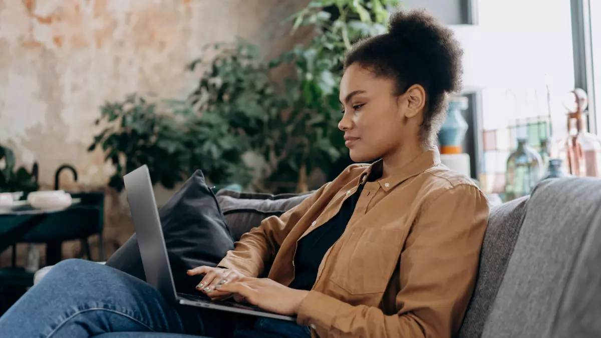 A woman sitting on a couch using a laptop.