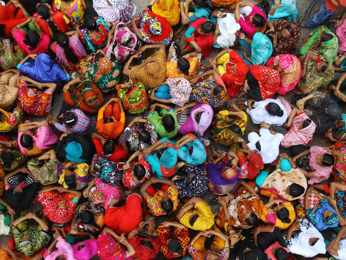 A large crowd of people sitting on the ground, all wearing colorful clothing