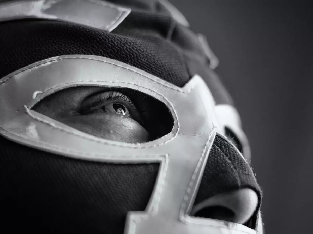 A close-up shot of a person wearing a wrestling mask, their eye peeking out from under the mask.