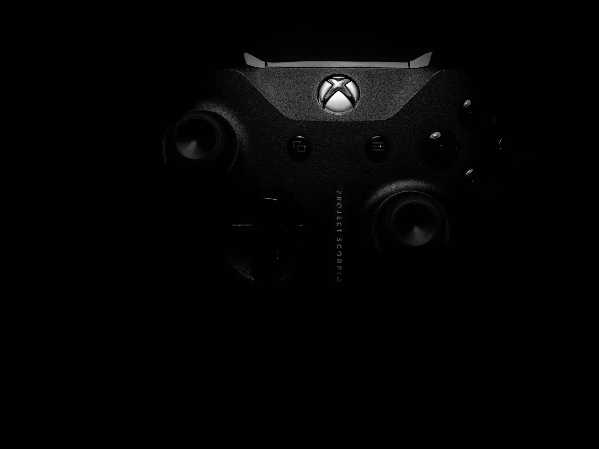 A close-up shot of a black Xbox controller with a blurred background, focusing on the buttons and the Xbox logo.