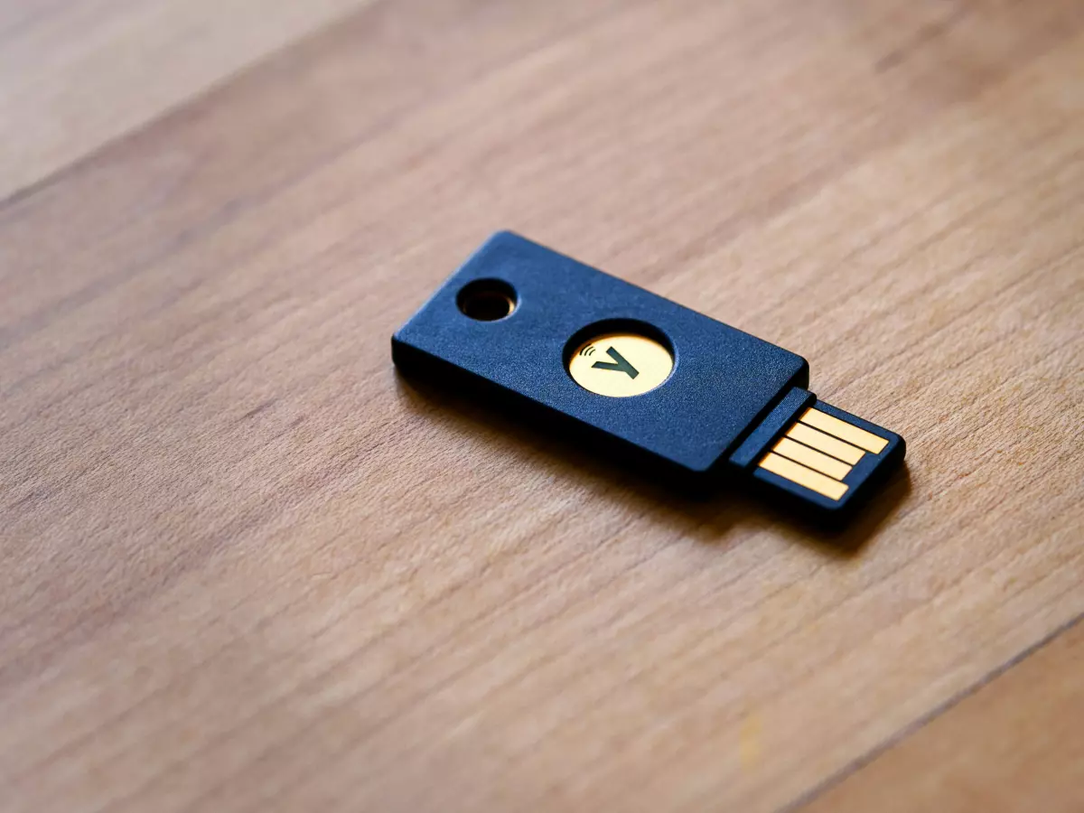 A YubiKey security key, black with a gold connector, on a wooden surface.